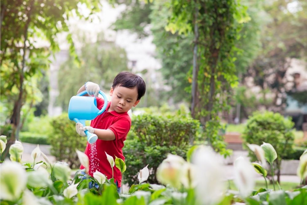 young boy using watering can outside